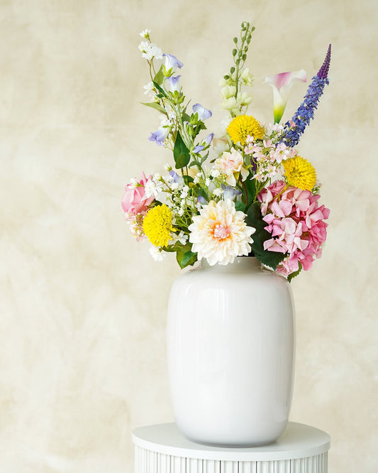 Zomerse kunstbloemen boeket Bella van Fan of Flowers opgesteld in een glanzende crème vaas Crema.