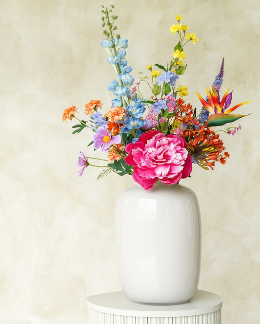 Vrolijk kleurrijk zijden veldboeket Fiera van Fan of Flowers gepresenteerd in glanzende vaas Crema.