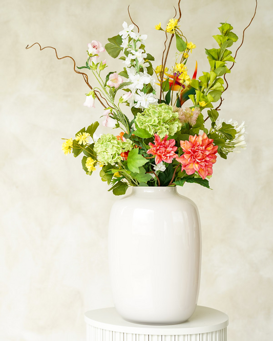Kunstboeket Verde van Fan of Flowers met frisse groene en koraaloranje accenten in glanzend witte vaas Crema.