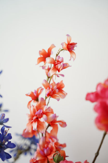 Detail van de opgaande koraaloranje zijden tak uit het boeket Cielo van Fan of Flowers.