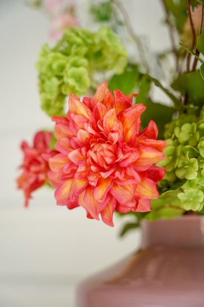 Close-up van de koraaloranje zijden dahlia en groene hortensia uit het boeket Verde van Fan of Flowers.