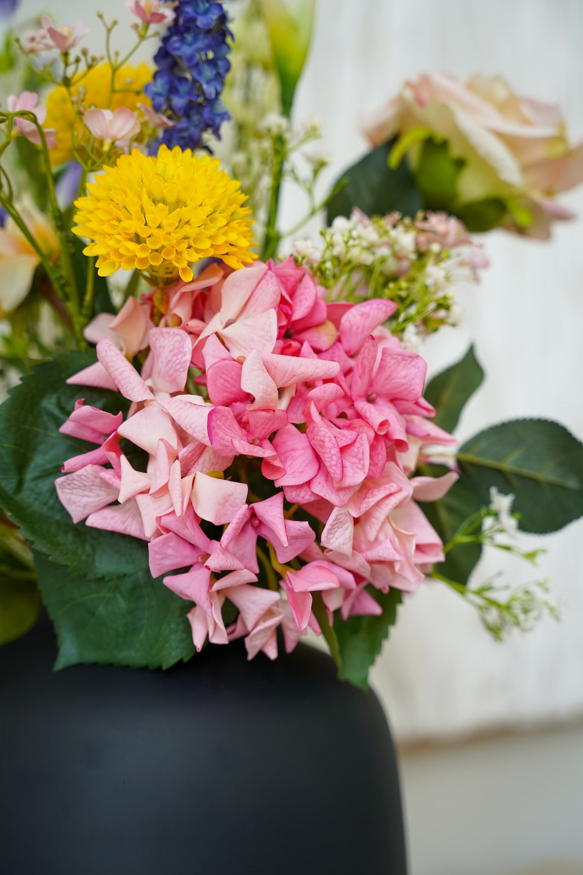 Detailopname van de felroze zijden hortensia en gele accentbloemen in boeket Bella van Fan of Flowers.