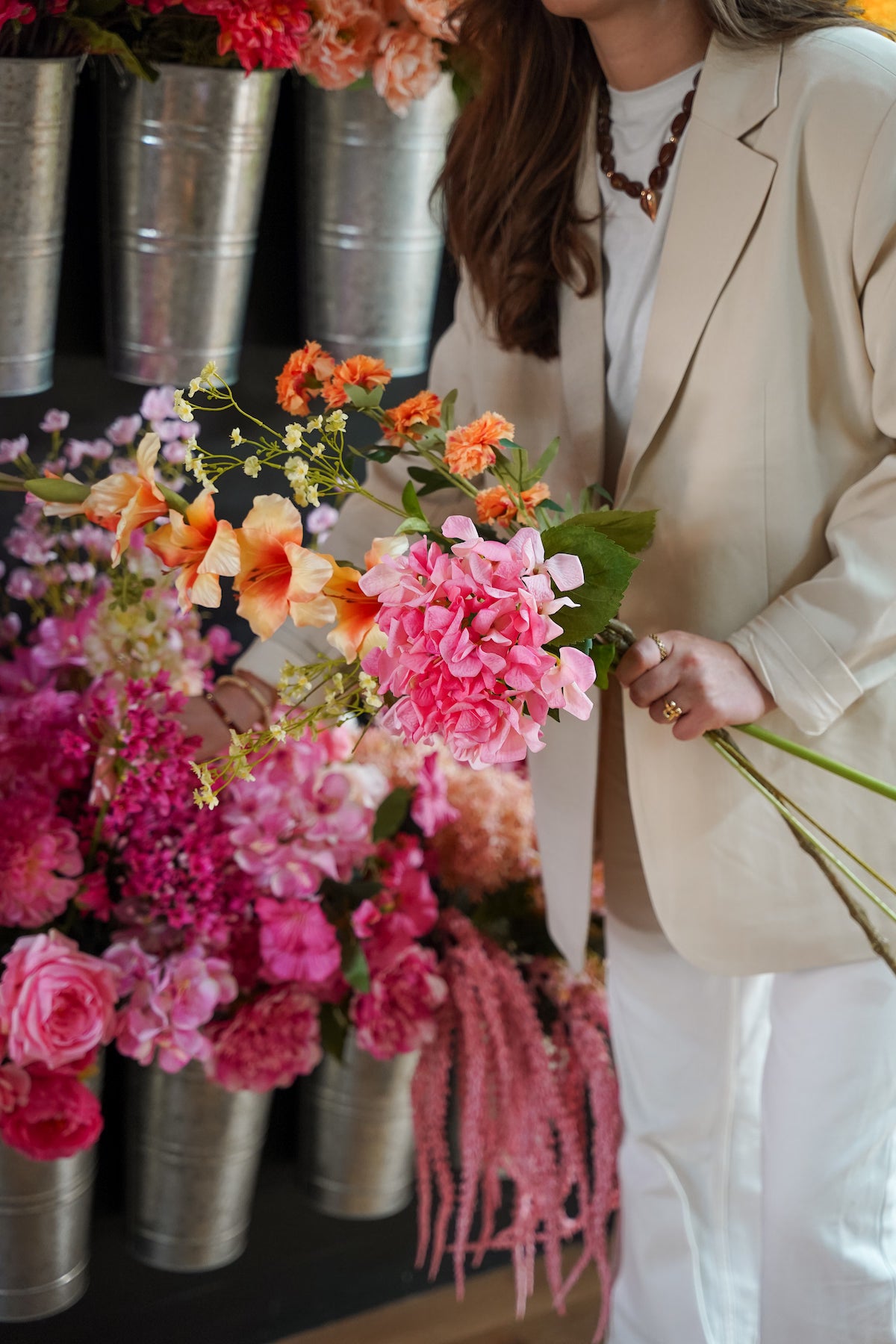 Femke Goossens selecteert roze en oranje zijden stelen bij de zinken koven in het atelier van Fan of Flowers.
