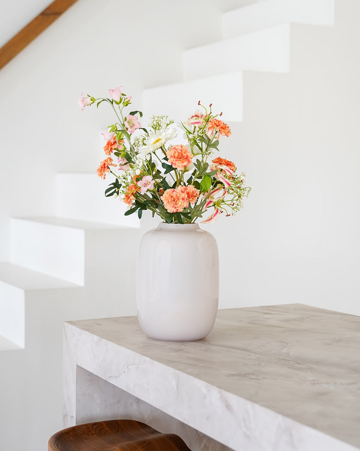 Glanzende crème-witte vaas Crema S van Fan of Flowers gevuld met een frisse oranje en roze zijden bloemencombinatie.