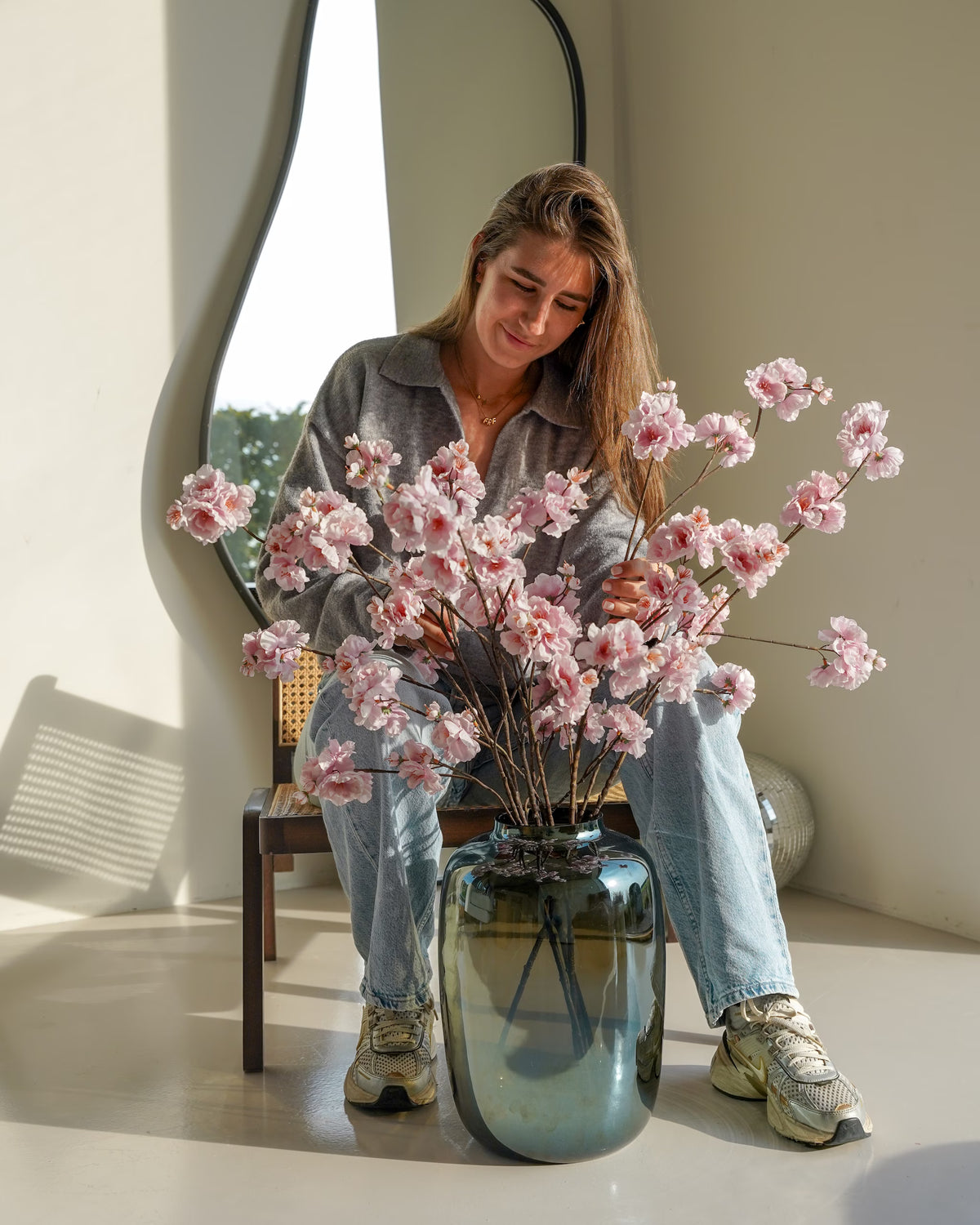 Femke Goossens schikt lichtroze zijden bloesems van Fan of Flowers in de spiegelende Vaas Glossy M.
