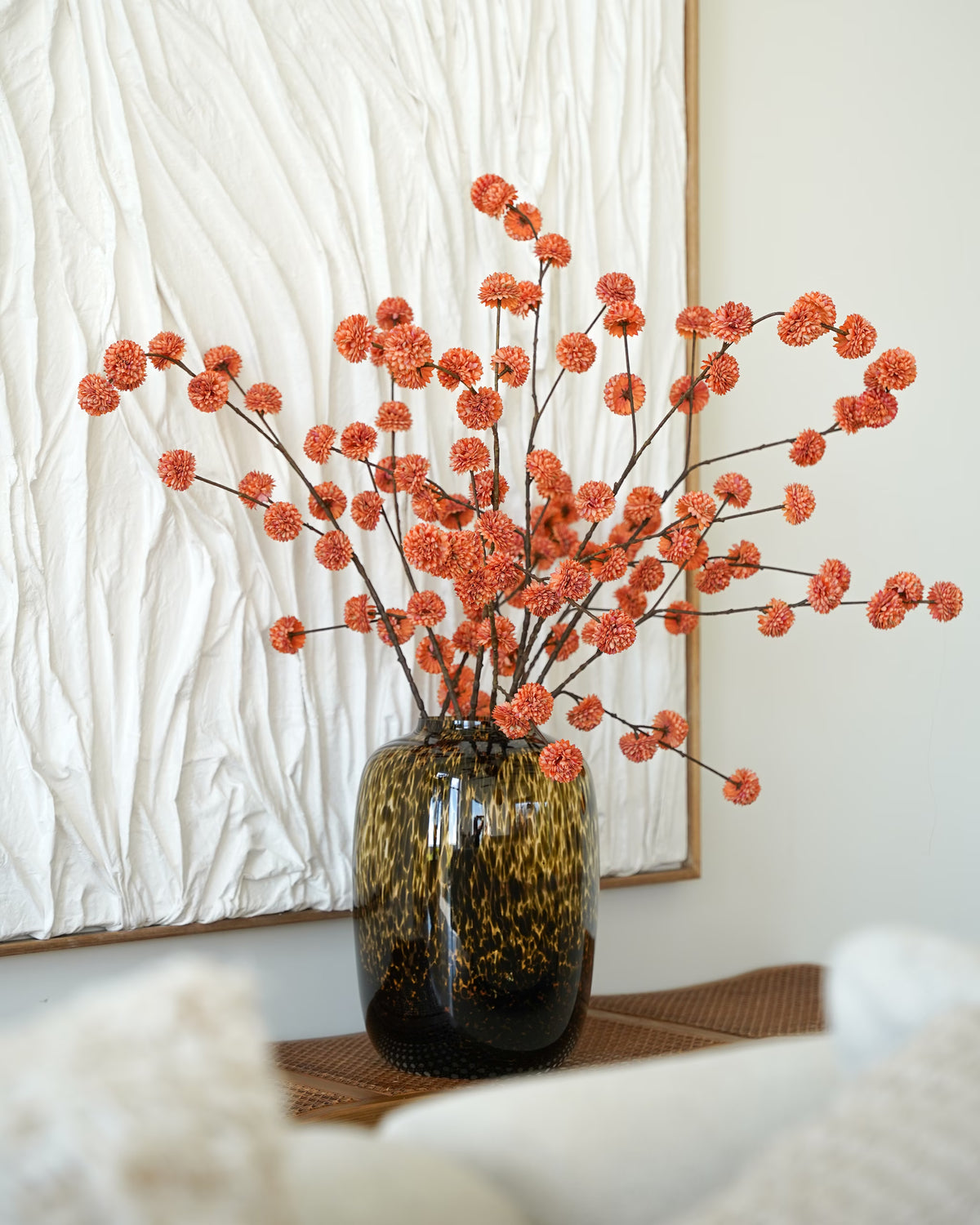 Glanzende tijgervaas Leo M van Fan of Flowers met hoge zijden takken met oranje bolbloemen, voor een wit wandkunstwerk.