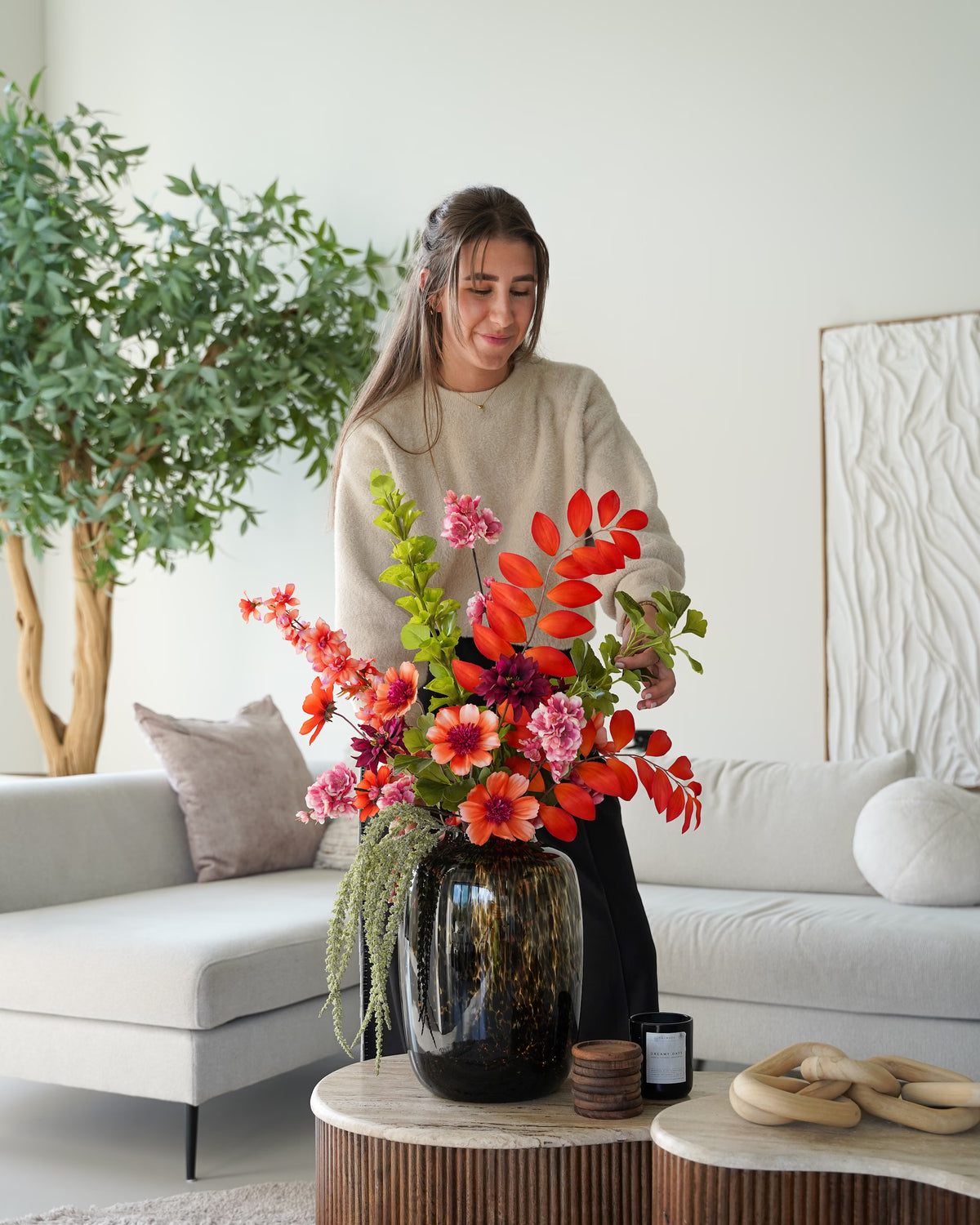 Femke Goossens schikt zijden boeket Palma met oranje en roze bloemen en groene takken in glazen tijgervaas Leo M van Fan of Flowers.