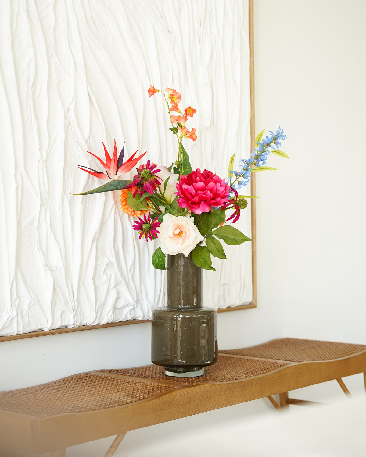 Vaas Madera met Zijden Boeket Paraíso, een paradijsvogelbloem en roze, oranje en blauwe bloemen op een houten bankje.