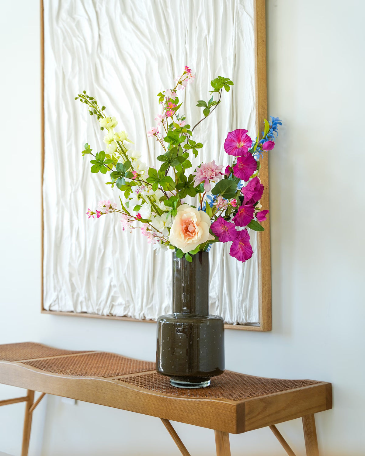 Vaas Madera met Zijden Boeket Rosa, paarse en blauwe bloemen en een crèmekleurige roos op een houten bankje.