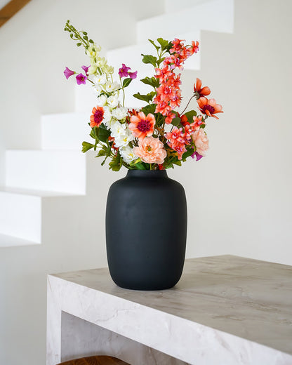 Luxe matzwarte vaas Negro M gevuld met een kleurrijk zijden veldboeket met oranje en roze kunstbloemen.