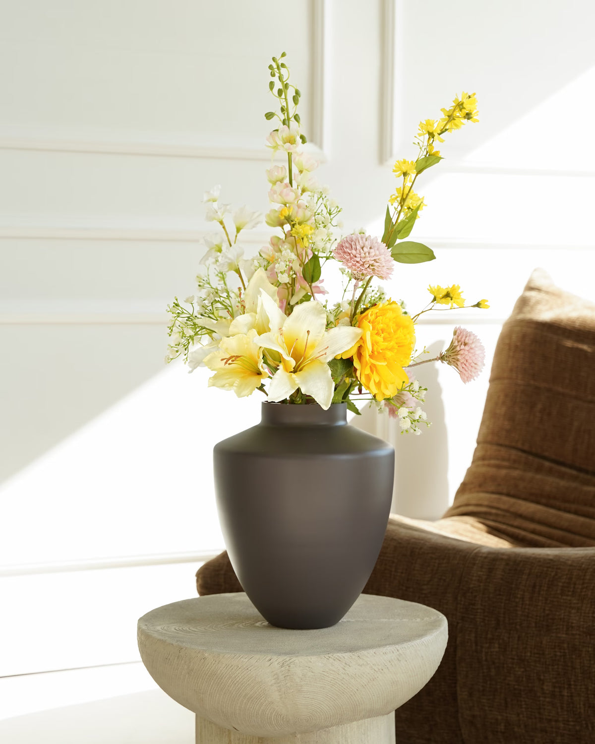 Vaas Tierra S met Zijden Boeket Mimosa in geel, wit en zachtroze op een houten bijzettafel naast een bruine fauteuil.