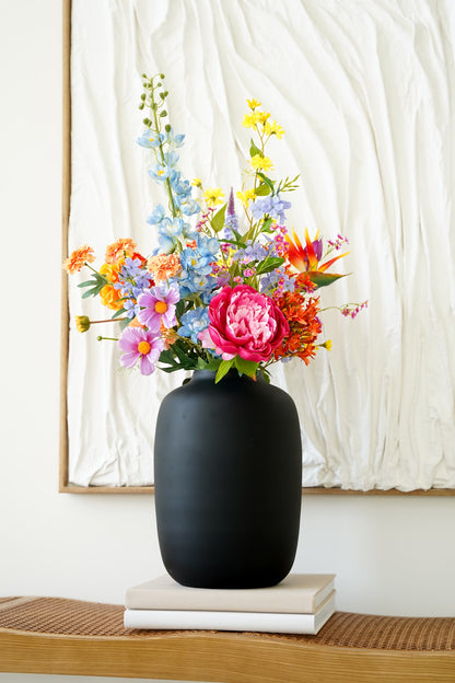 Stijlvol kleurrijk zijden boeket Fiera van Fan of Flowers in vaas Negro gepresenteerd in een modern interieur.