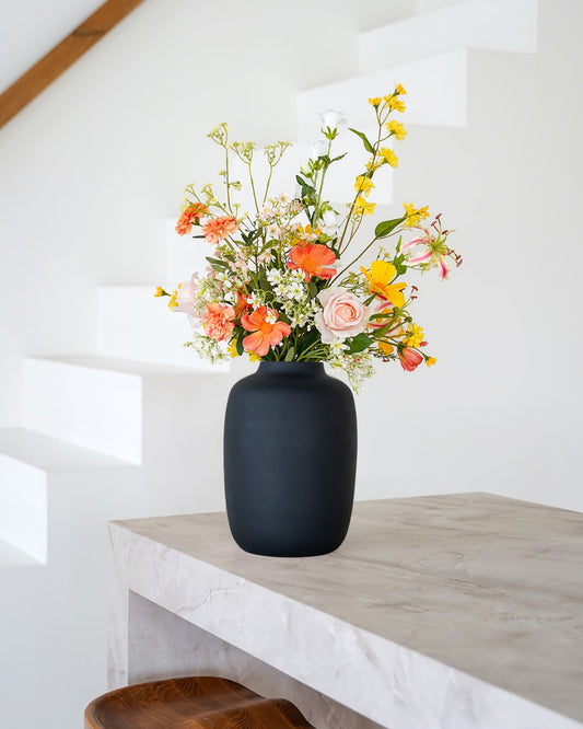 Fris geel met oranje zijden boeket Fio van Fan of Flowers stijlvol gepresenteerd in matzwarte vaas Negro.