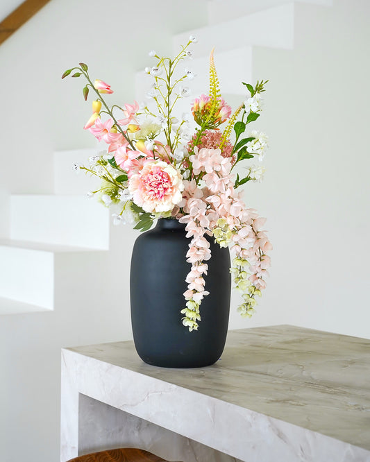 Stijlvol zachtroze zijden boeket Nube van Fan of Flowers elegant gepresenteerd in matzwarte vaas Negro.