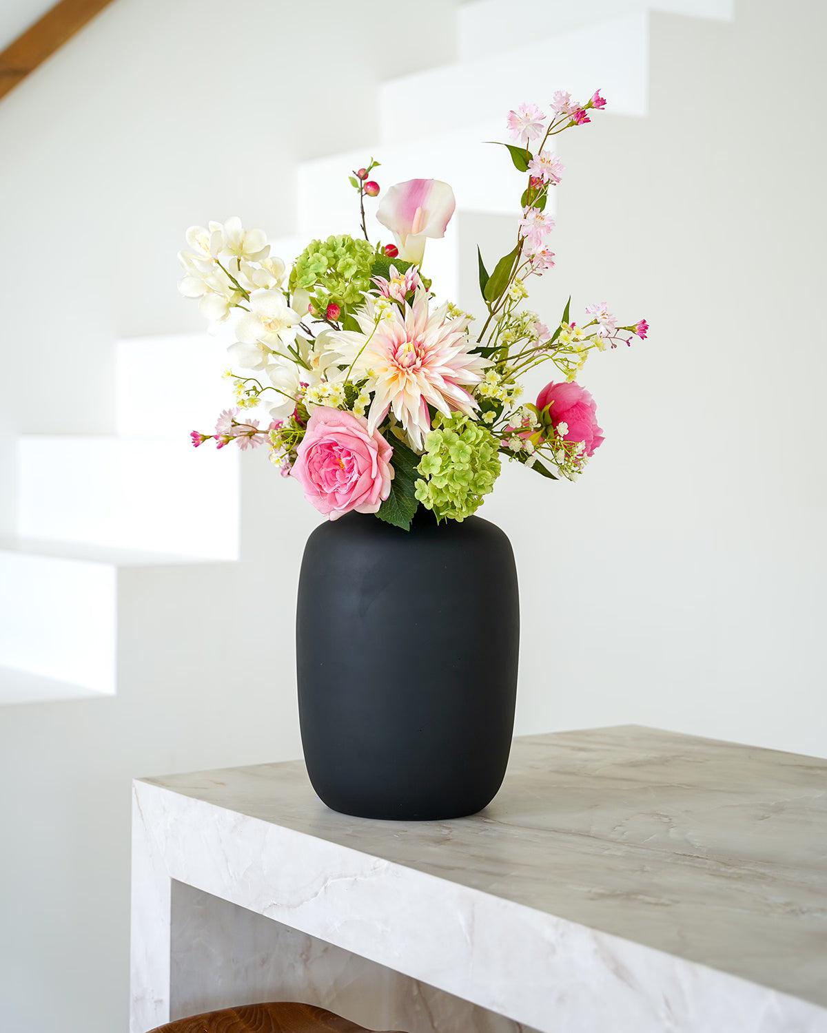 Stijlvolle presentatie van het zijden bloemen boeket Lola in de matzwarte vaas Negro van Fan of Flowers.