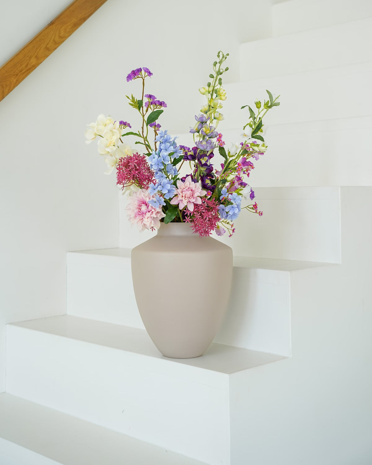 Prachtig kleurrijk zijden boeket Amatista van Fan of Flowers sfeervol gestyled op een strakke witte trap.