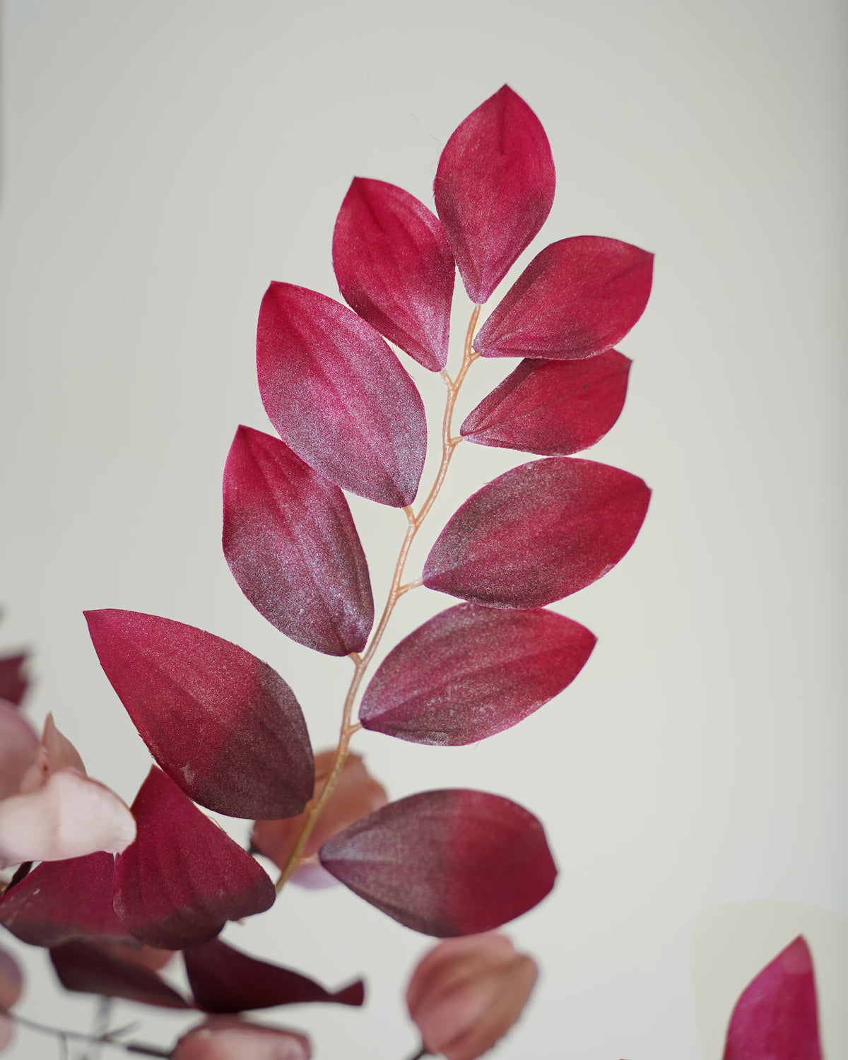Detail van een tak met bordeauxrode zijden bladeren uit boeket Amaya van Fan of Flowers.