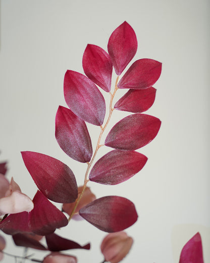 Detail van een tak met bordeauxrode zijden bladeren uit boeket Amaya van Fan of Flowers.