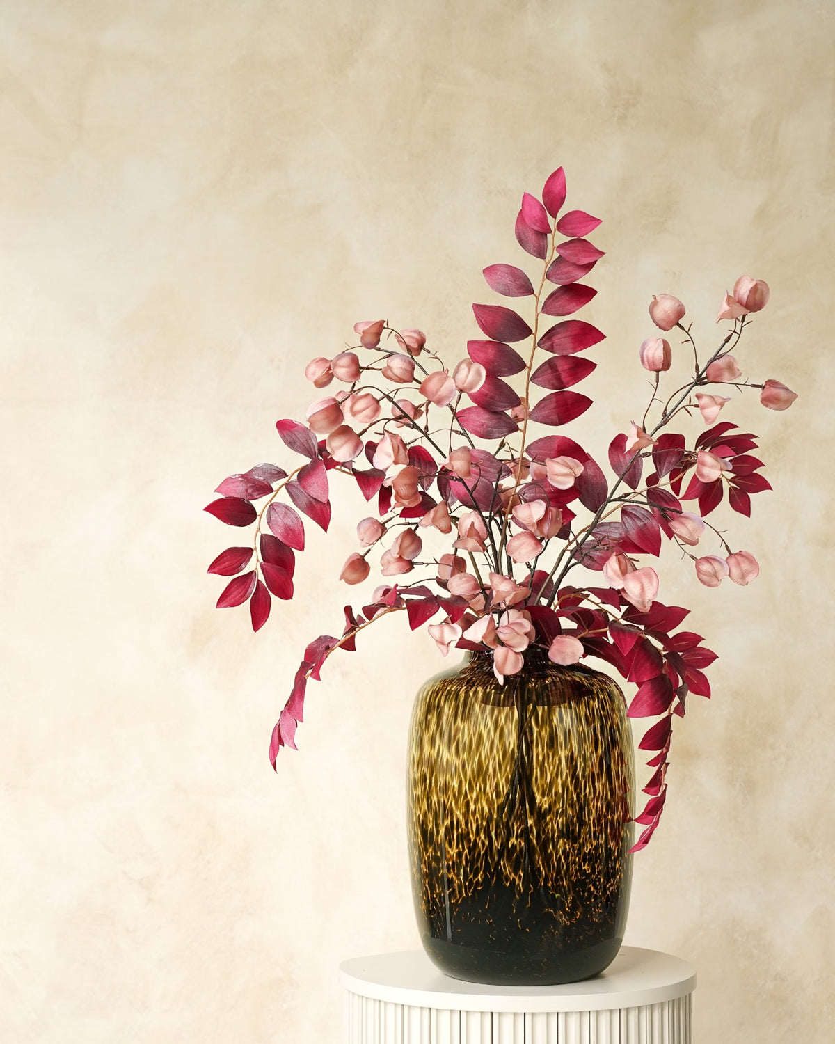 Zijden boeket Amaya van Fan of Flowers met bordeauxrode bladeren en zachtroze lampionnetjes in tijgervaas Leo.