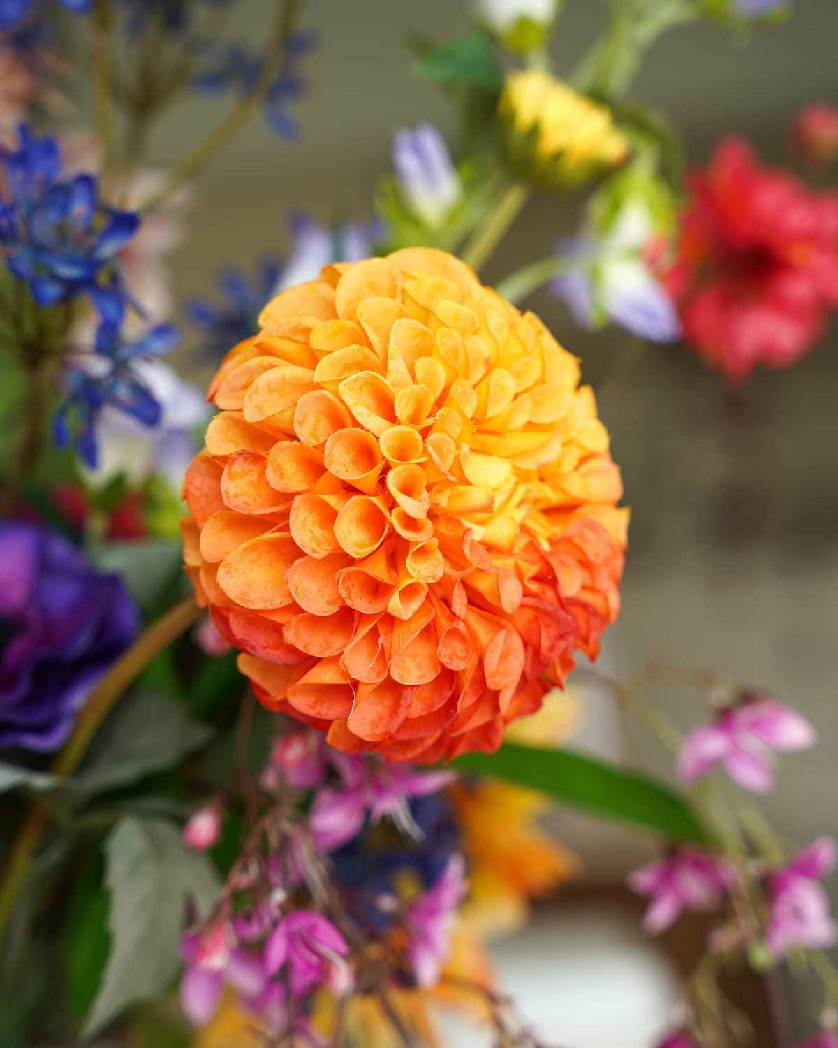 Detail van een ronde oranje zijden bloem met dicht opeengepakte bloemblaadjes in boeket Chica van Fan of Flowers.