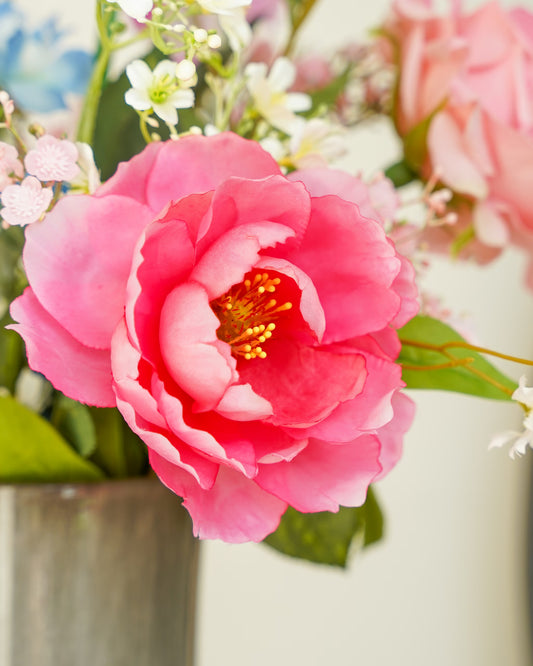 Close-up van een roze zijden pioenroos met gele meeldraden, omringd door kleine bloemen in Boeket Dulce.