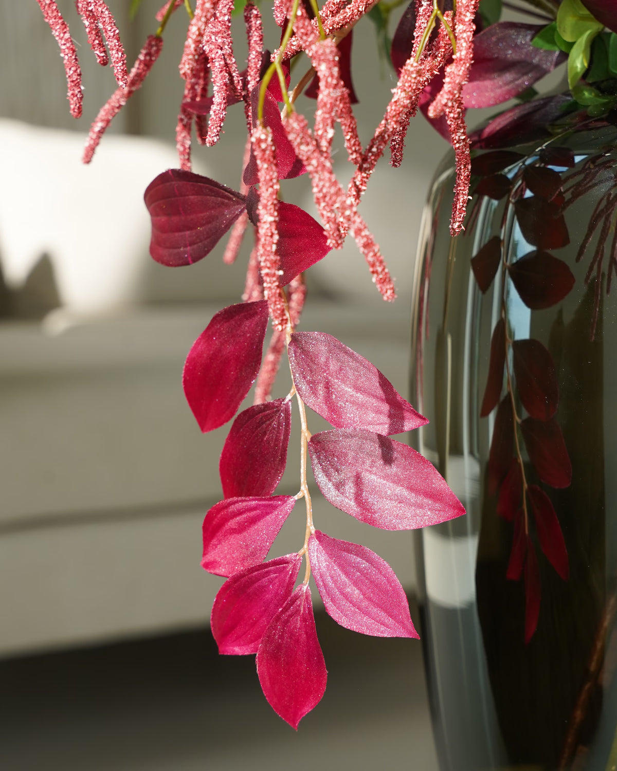 Detail van bordeauxrode bladeren en roze afhangende takken langs een glanzende vaas in zijden boeket Lila van Fan of Flowers.