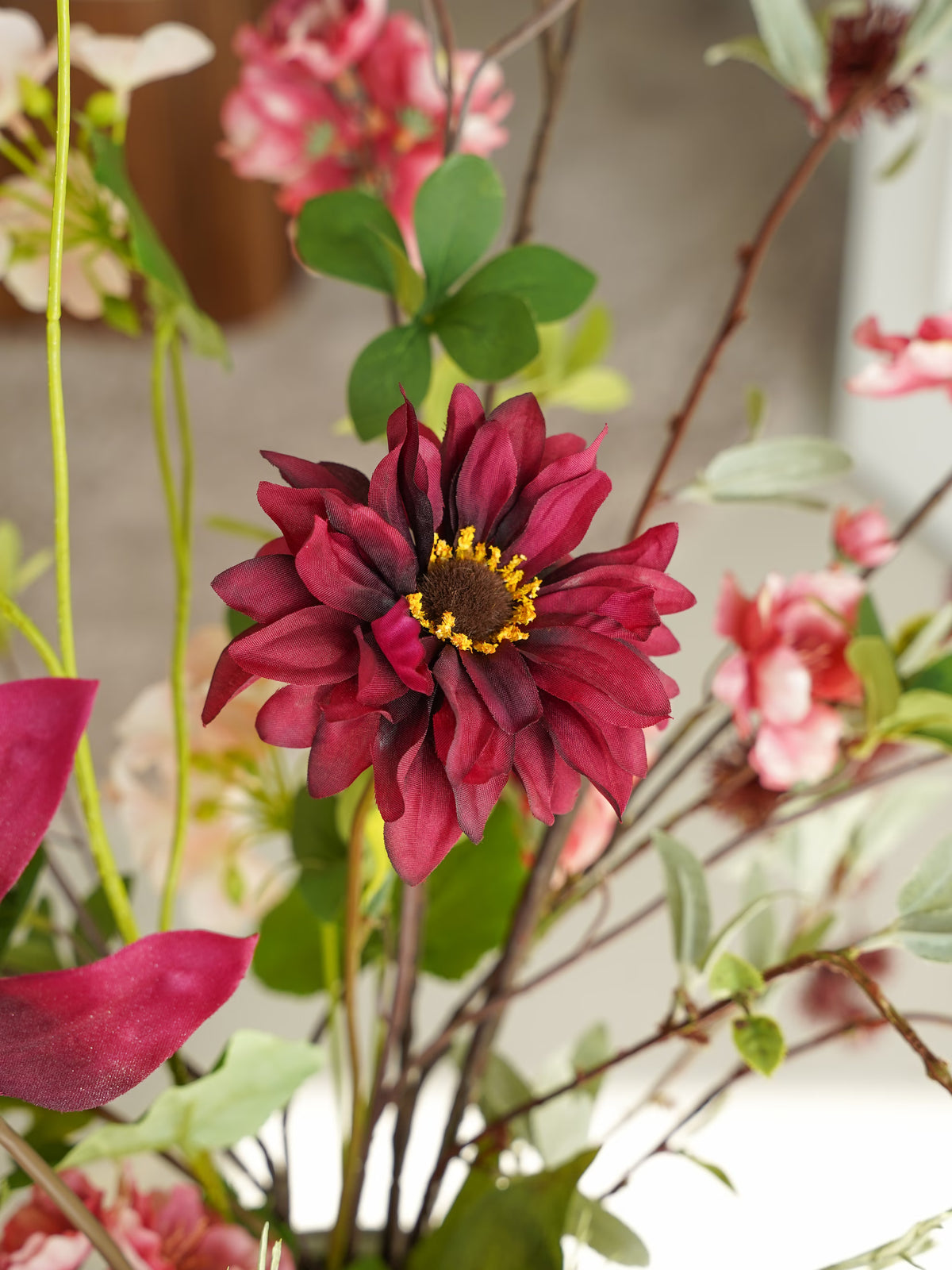 Detail van een bordeauxrode zijden bloem met een donker hart en gele accenten in boeket Lila van Fan of Flowers.