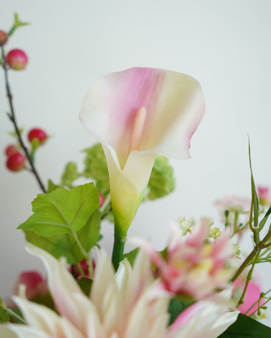 Close-up van een zijden calla in wit en roze, met groen blad en roze accenten in Boeket Lola.