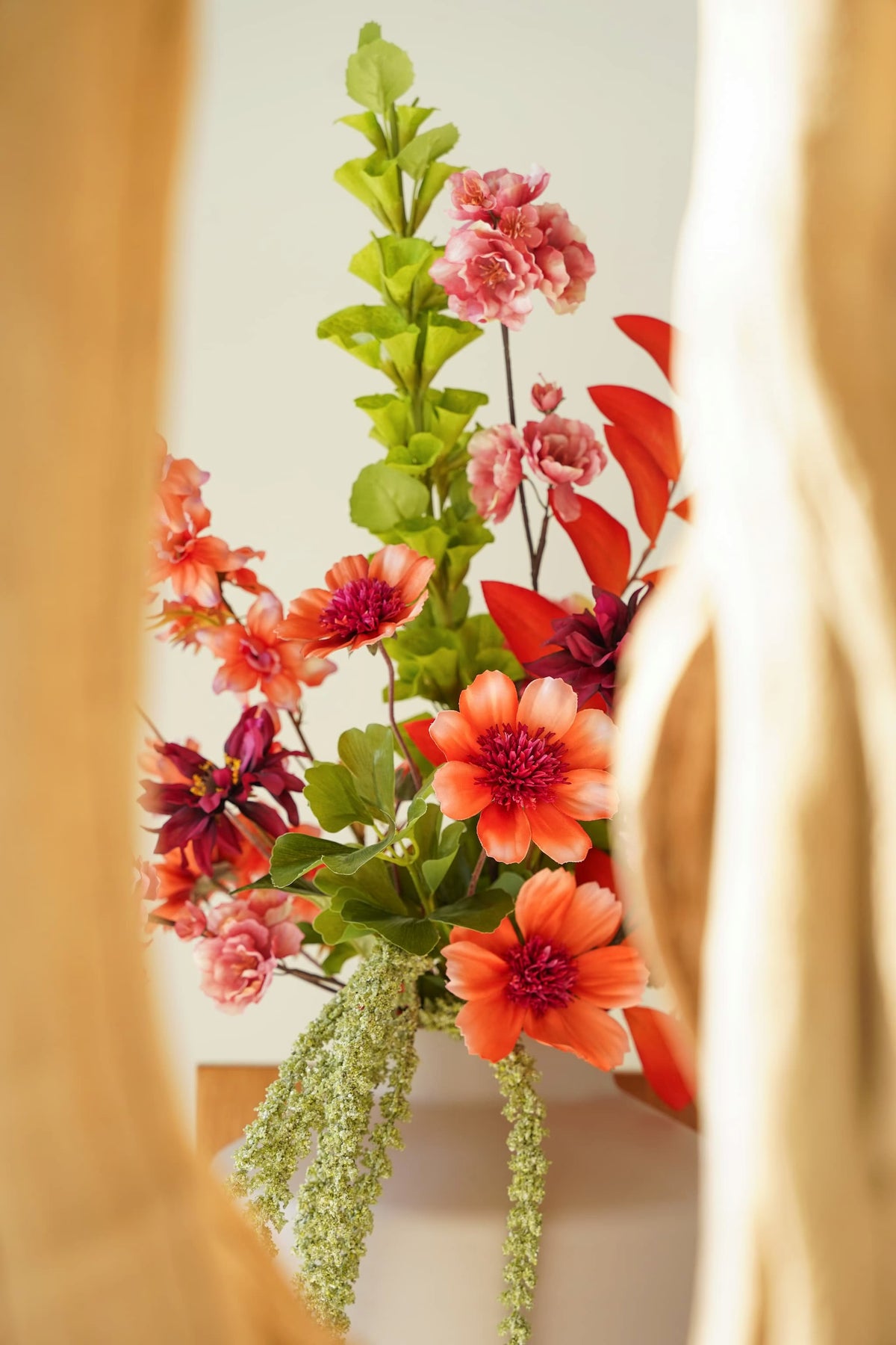 Oranje zijden bloemen met donkerroze harten, roze bloesem en frisgroen blad in boeket Palma van Fan of Flowers.