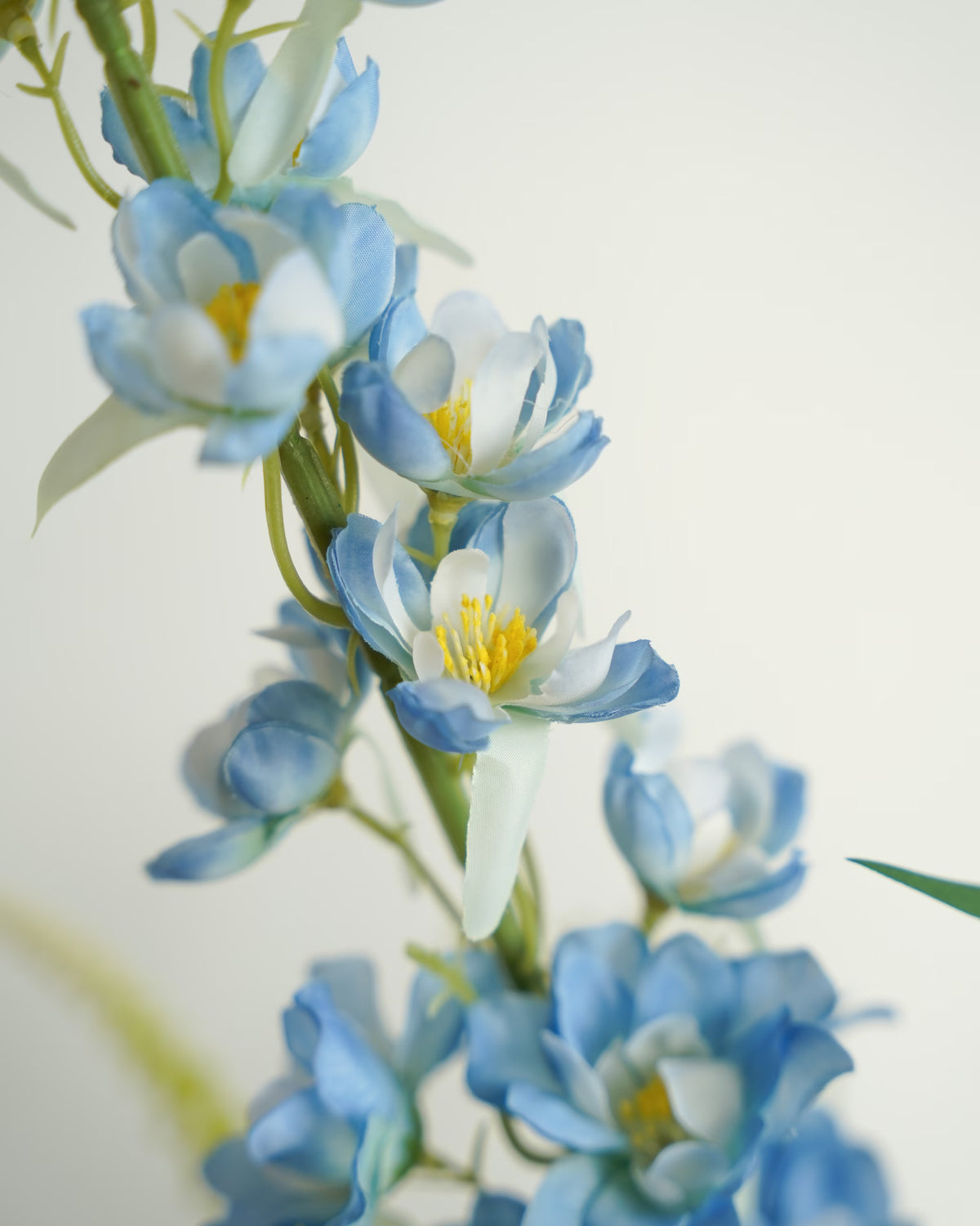 Detail van lichtblauwe zijden bloemen met witte accenten en gele meeldraden aan een hoge steel in boeket Rio van Fan of Flowers.
