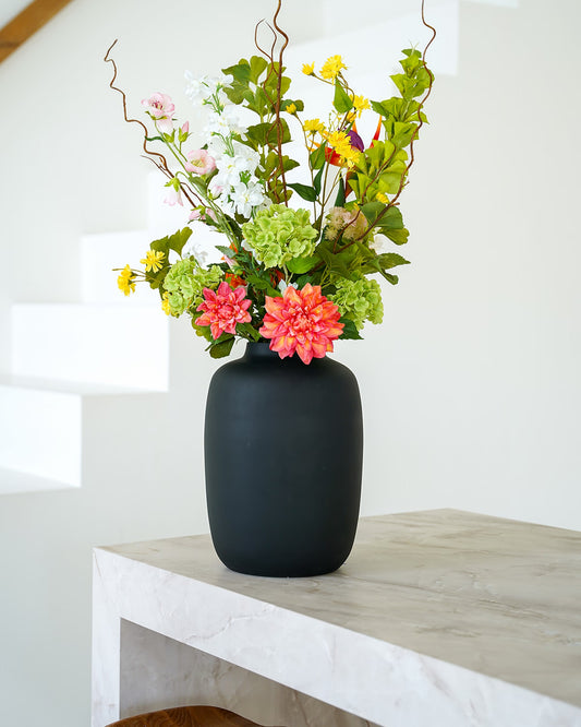 Fris groen zijden boeket Verde van Fan of Flowers in matzwarte vaas Negro sfeervol gestyled bij een moderne trap.