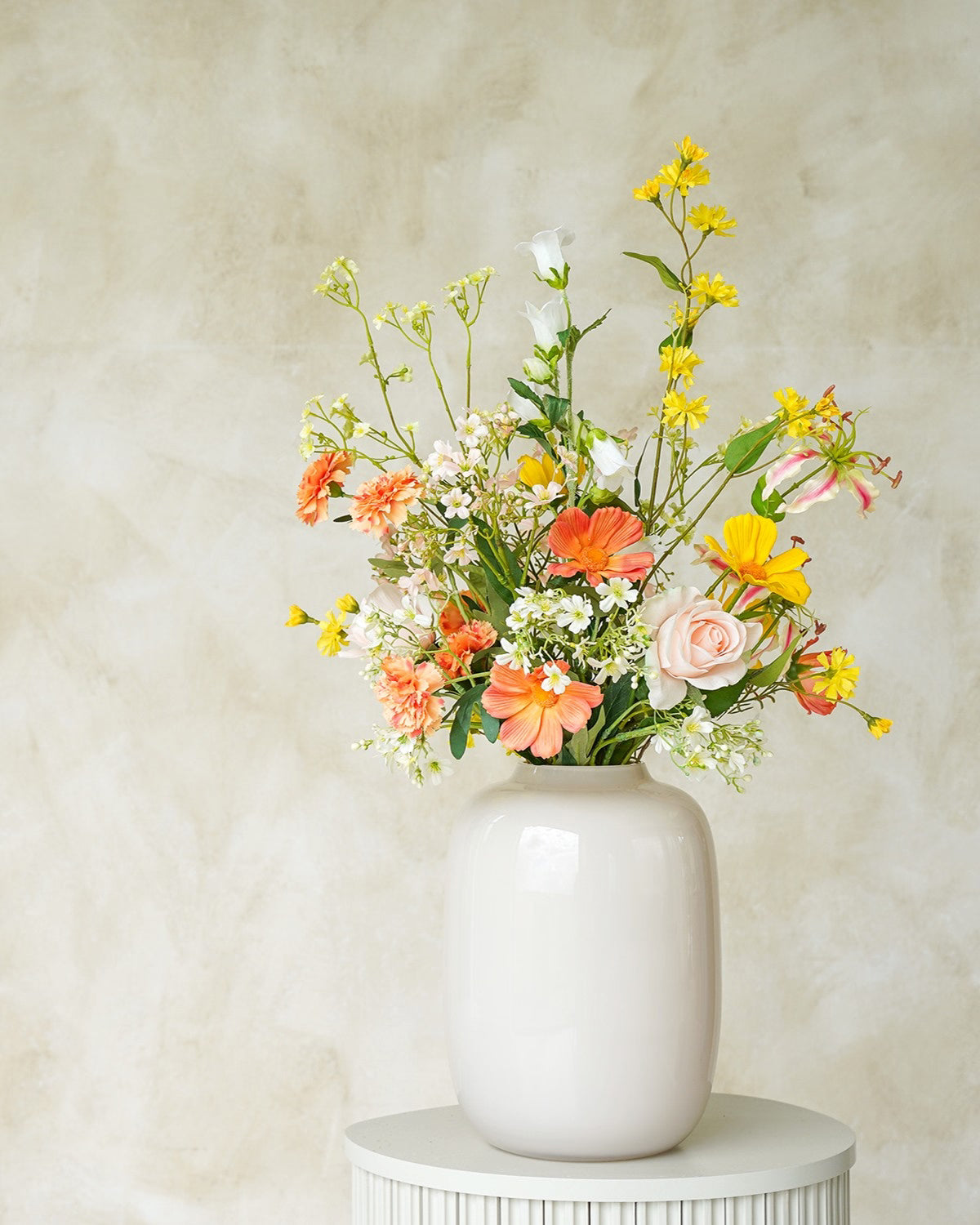 Sfeervol geel met oranje zijden boeket Fio uit de collectie van Fan of Flowers gepresenteerd in vaas Crema.