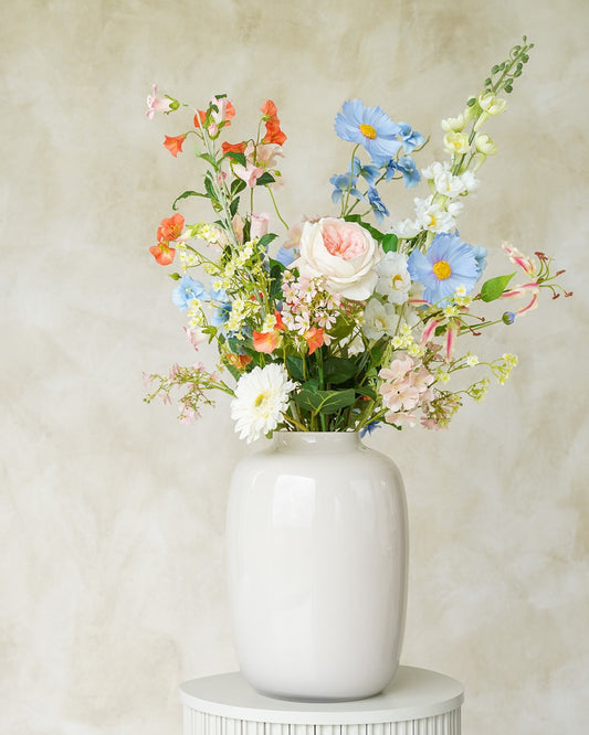 Sfeervol zachtblauw en pastelkleurig zijden boeket Mari uit de collectie van Fan of Flowers gepresenteerd in vaas Crema.
